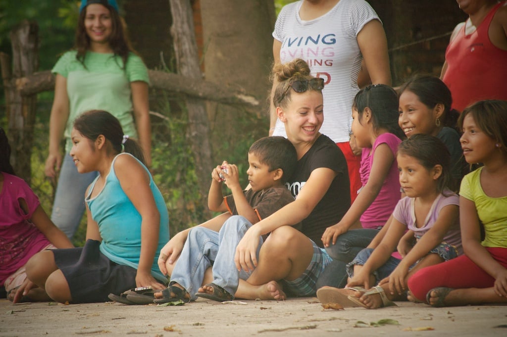 Young woman sitting on the ground with children