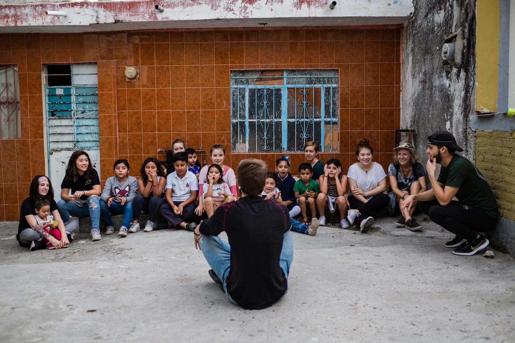 Young YWAM missionary speaking to a group of children while doing ministry in Mexico